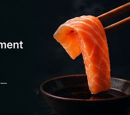 Sashimi held with chopsticks over soy sauce